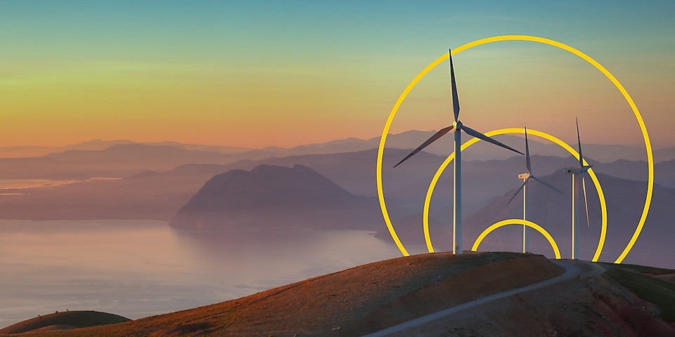 Foto van drie windmolens op een heuvel met een grafische weergave van het symbool voor het doel om netto nul uitstoot te bereiken.