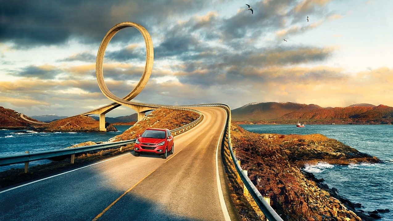 Red car driving on the road by the river