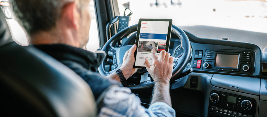 Homme au volant d’un camion, tenant une tablette