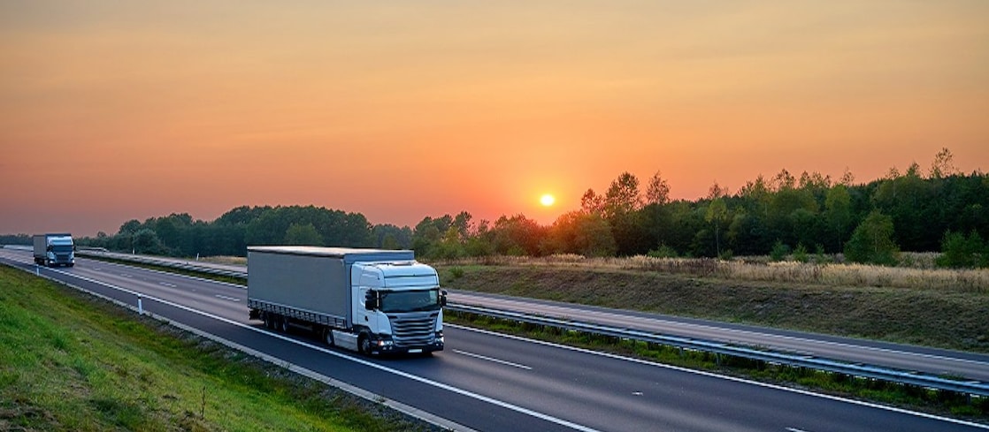 Trucks on a highway at sunset