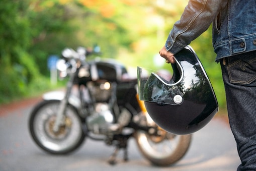 Un motocycliste tenant son casque.