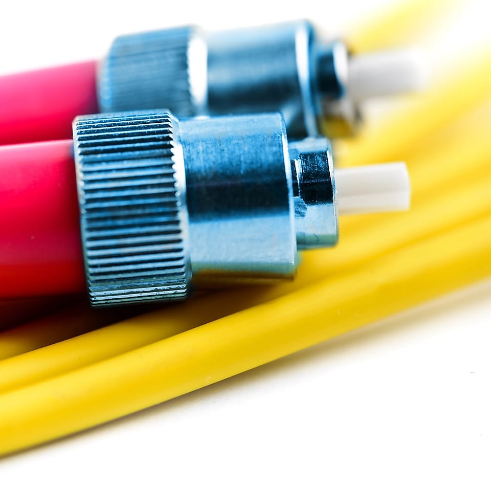 Les deux extrémités d'un câble à fibres optiques placées sur un autre câble jaune