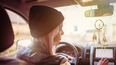 Une jeune femme consulte les instructions du GPS de sa voiture