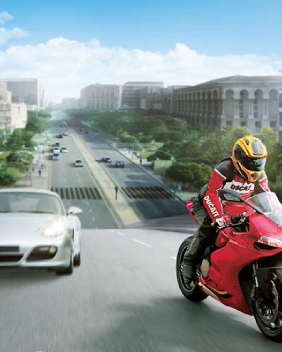 Moto rouge et motard sur une route avec des voitures et des bâtiments en arrière-plan