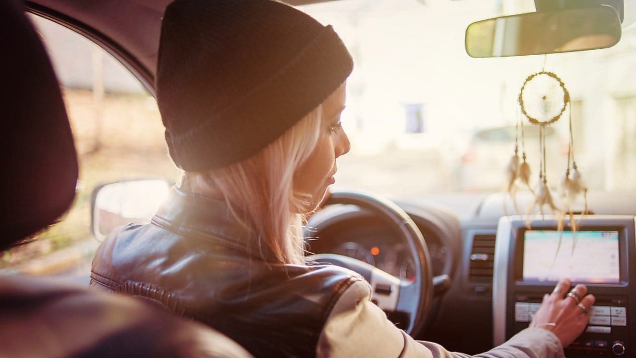 Une jeune femme consulte les instructions du GPS de sa voiture