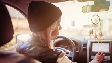 Une jeune femme consulte les instructions du GPS de sa voiture