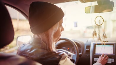 Une jeune femme consulte les instructions du GPS de sa voiture