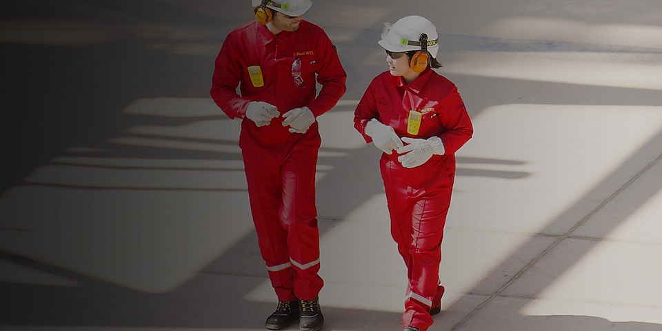 Mannelijke en vrouwelijke medewerker in rode overalls en witte helmen en gehoorbescherming
