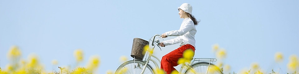 Een jonge vrouw die op een fiets door een weiland met bloemen rijdt