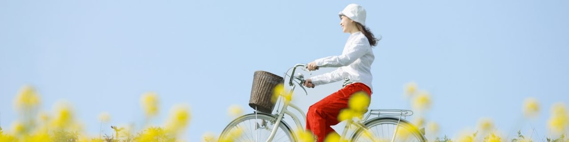 Een jonge vrouw die op een fiets door een weiland met bloemen rijdt