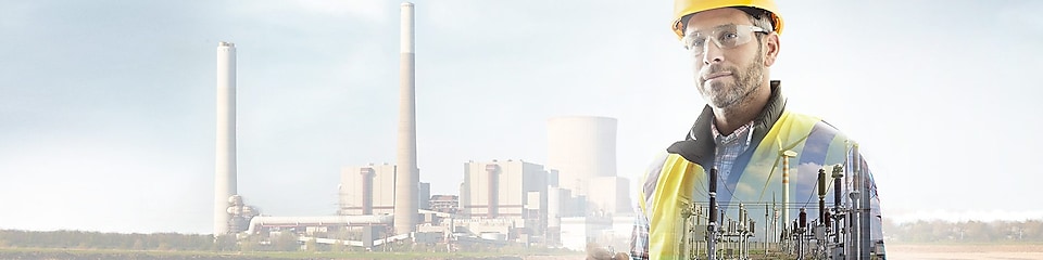 werknemer met gele helm met op de achtergrond een elektriciteitscentrale
