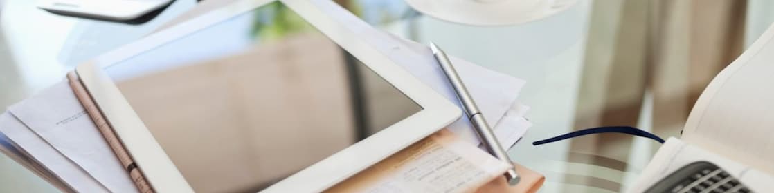 Tablet computer, newspaper, coffee cup and cell phone on desk