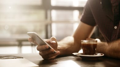 Man met smartphone en kopje koffie