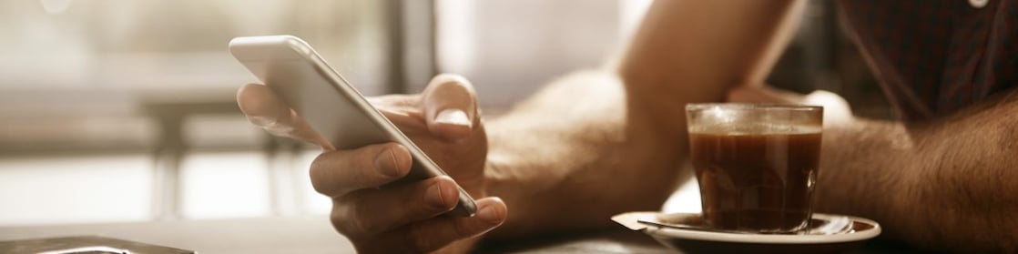 Man met smartphone en kopje koffie