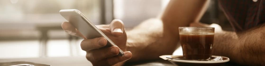 Man met smartphone en kopje koffie