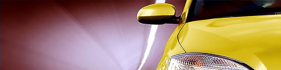 Voorzijde van een gele auto die door een tunnel rijdt, rechtervoorlicht en zijspiegel in beeld