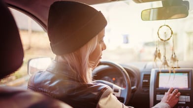Een jonge vrouw leest de instructies op het navigatiesysteem van haar auto