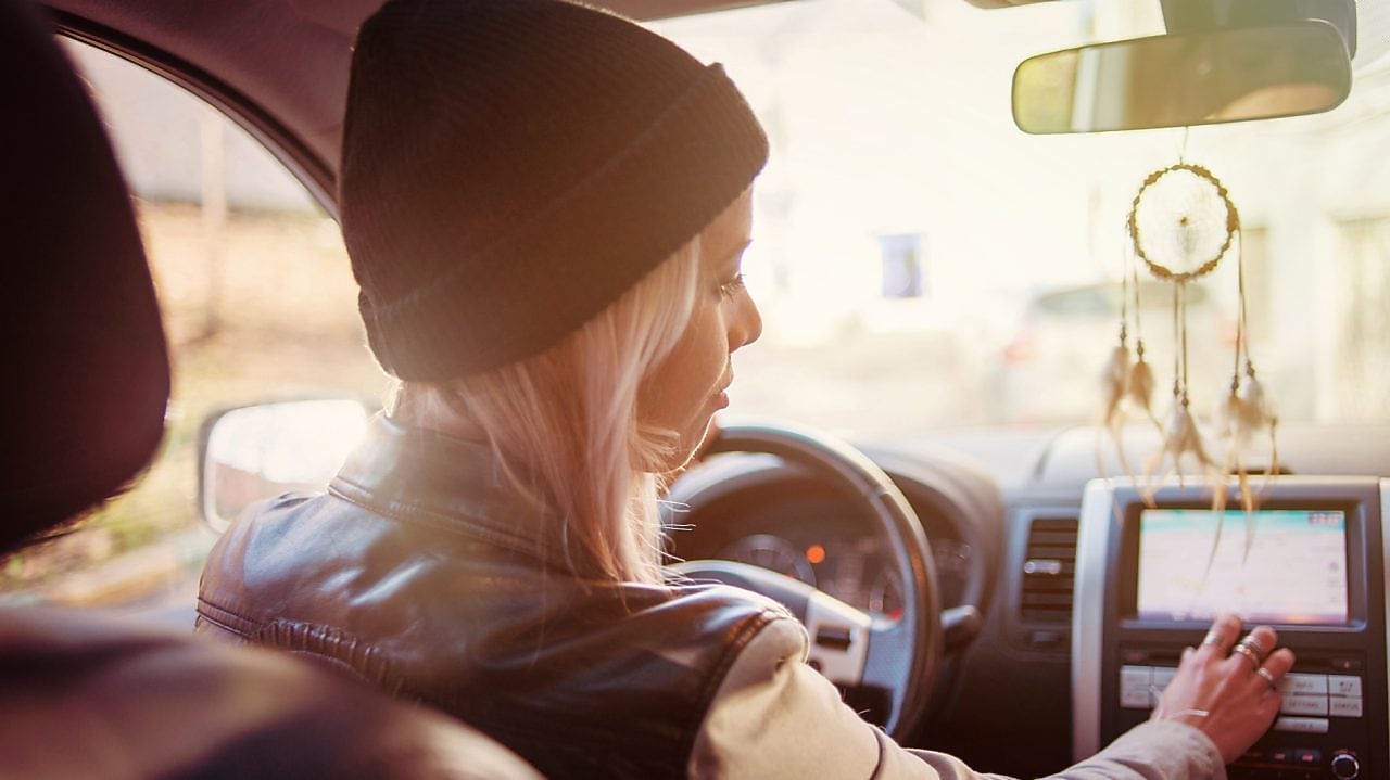 Een jonge vrouw leest de instructies op het navigatiesysteem van haar auto