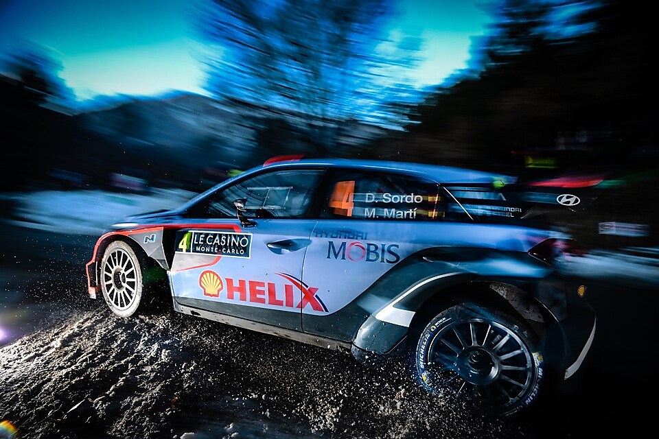 Rally-auto rijdt snel in het ochtendlicht in het wereldkampioenschap rally