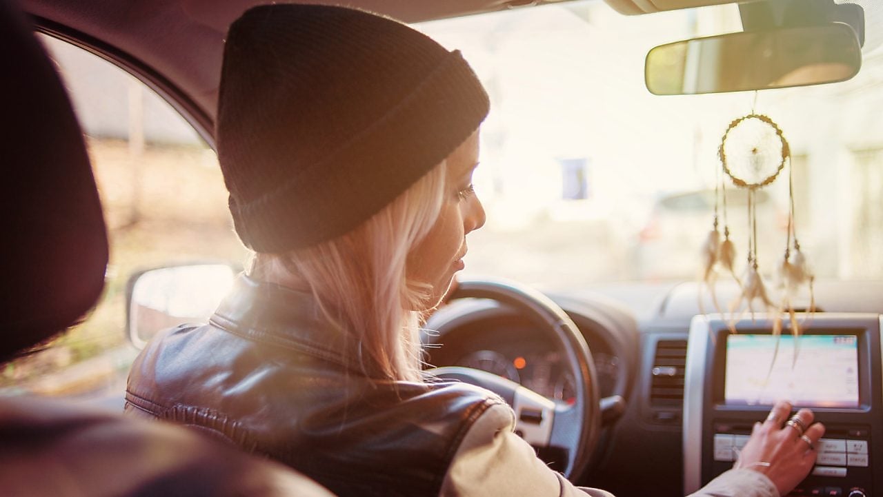 Een jonge vrouw leest de instructies op het navigatiesysteem van haar auto